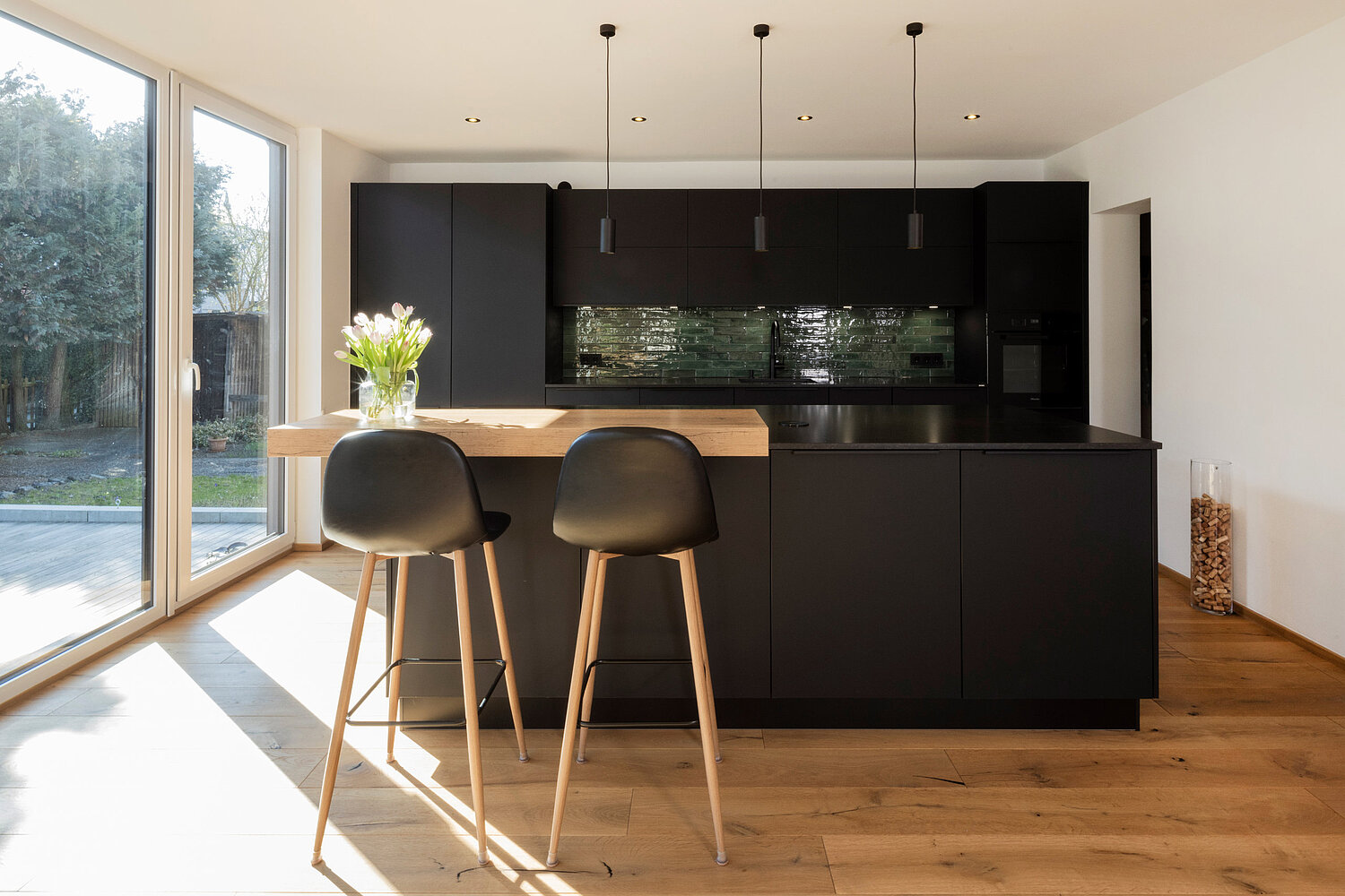 Designküche mit Essbereich von Lorinser Moderne Küche mit dunklen Fronten, Essbereich und stilvoller Beleuchtung, realisiert vom Küchenstudio Lorinser